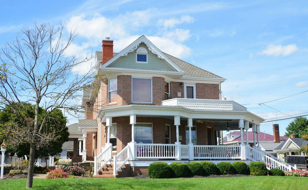 Bright, freshly cleaned brick home with a white wrap-around porch